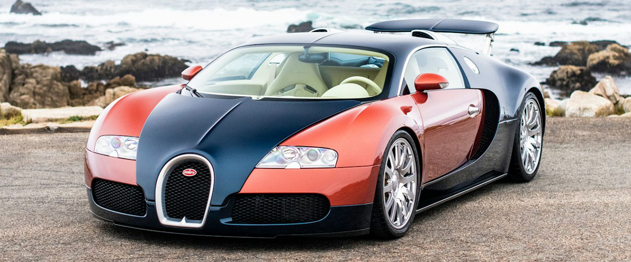 Face avant de la Bugatti Veyron La Maison Pur Sang 20 Years bicolore Petrol Blue et Rouge Rembrandt stationnée en bord de mer à Pebble Beach