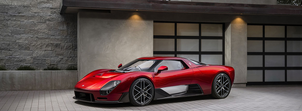 Supercar McLaren McL 6GT rouge stationnée devant une villa moderne