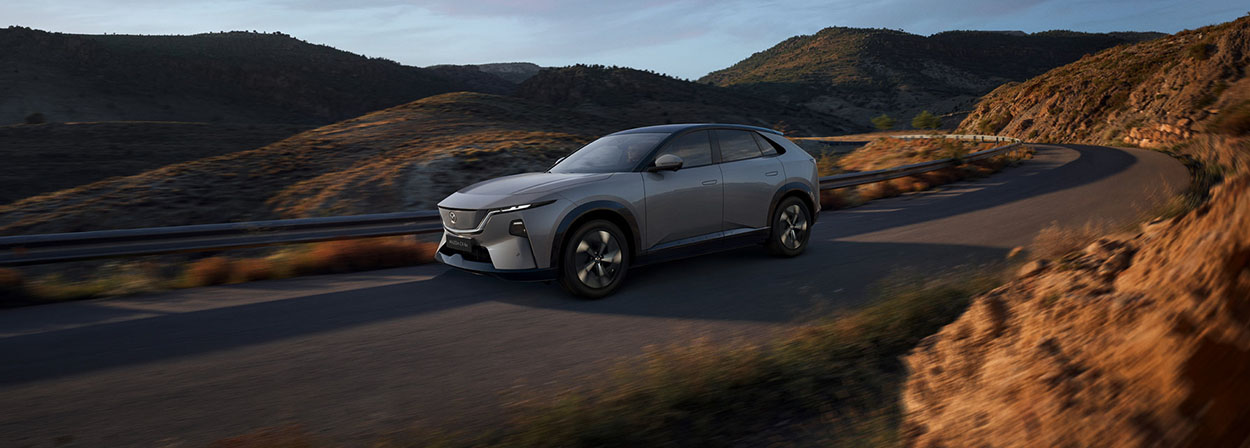 Mazda Cx 6 e 2026 stationné sur la route devant une montagne