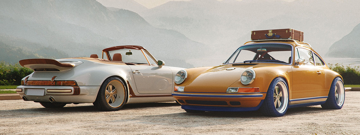 Les deux Porsche 911 Reimagined by Singer pour Louis Vuitton : le cabriolet Classic Turbo blanc et le coupé Classic safran avec sa malle de toit, côte à côte devant un paysage de montagnes.