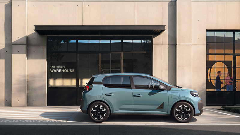 Nouvelle Dacia Spring  verte en face d'un bâtiment