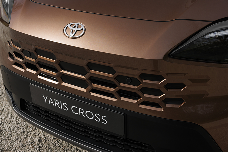 Gros plan sur la nouvelle calandre en nid d'abeille de la Toyota Yaris Cross 2026, peinte ton caisse avec le logo Toyota central.