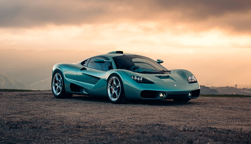 Supercar Gordon Murray S1 vert métallisé vue de trois-quarts face sur route au coucher du soleil