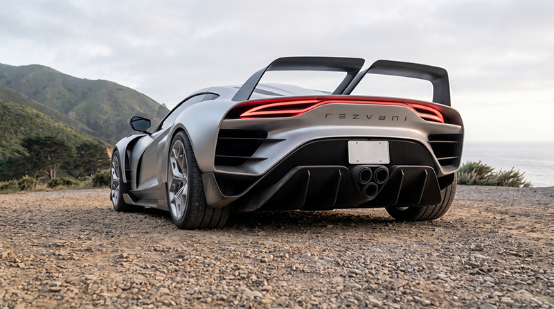 Vue arrière en contre-plongée d'une Rezvani Beast X gris mat, montrant son imposant aileron double, son diffuseur en carbone et sa triple sortie d'échappement centrale.