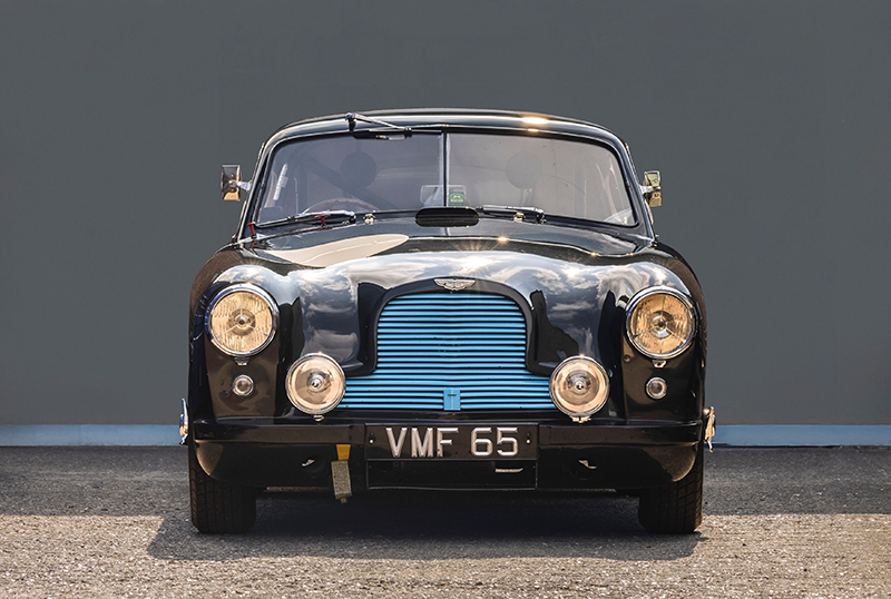 Vue avant d'une Aston Martin DB2 ancienne noire avec calandre bleue et plaque VMF 65.