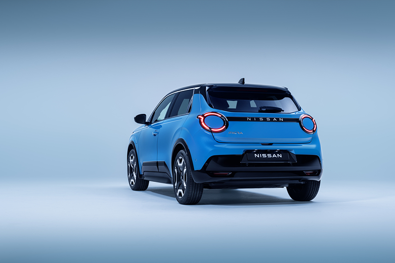 4 view of Micra in blue gear color showing signature lit headlamps. nissan name plate driver passenger doors wheels and black bumper copie